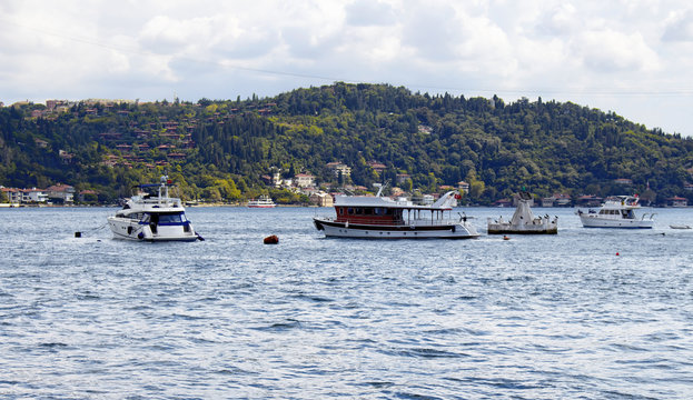 View of bay of luxury neighborhood Bebek on European side of Istanbul. Yachts, fishing boats are parked on Bosphorus. Residential buildings on Asian side are in the background. Cloudy autumn day.