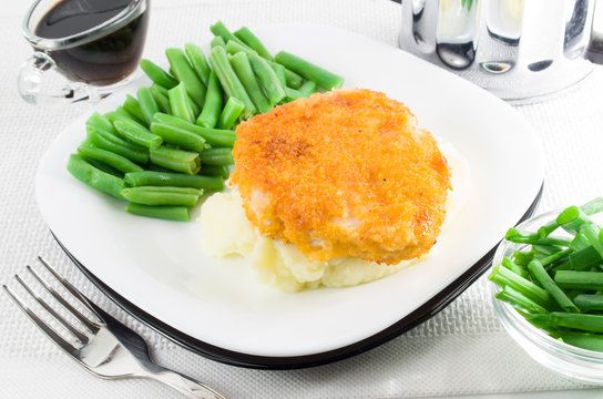 Piece of chicken fried in breadcrumbs, green beans and mashed po