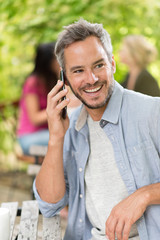 Handsome man sitting at a terrace cafe and using a smartphone