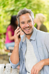 Handsome man sitting at a terrace cafe and using a smartphone