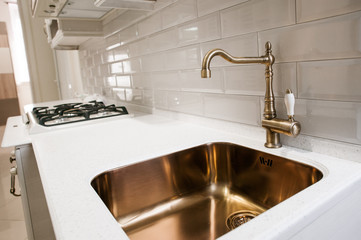Angle view of kitchen sink with gold faucet