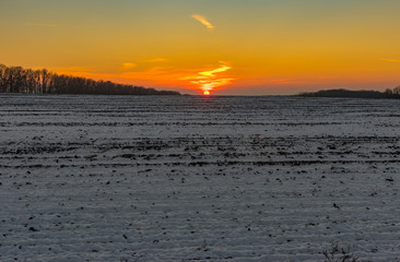 Sunset over agricultural field at winter season in Ukraine