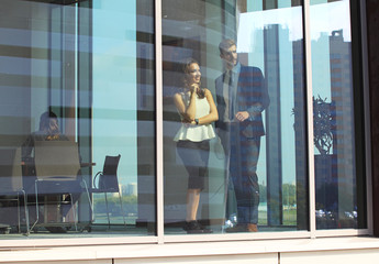 Confident business partners walking down in office building and talking.