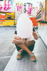 Chico joven tomando algodón de azúcar en una feria 