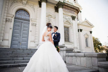 Fototapeta premium Wedding couple. Young asian bride and groom hugging on castle background after wedding ceremony