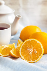 Lemon with cup of tea and teapot in background. Copy space