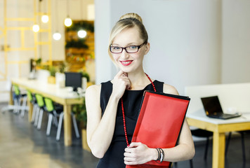 Happy student girl smiles and holds folders in  red and black colors in her hands