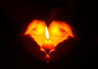 Hands and  burning candle in dark