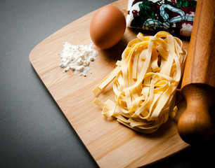 italian tagliatelle displayed on a chopping board together with some ingredients