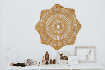 Wicker star on wall above variety of ornate objects on shelf