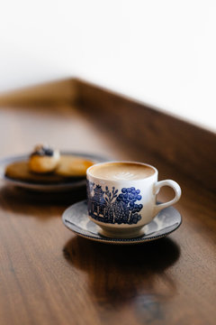 Cup of coffee on table beside plate of biscuits