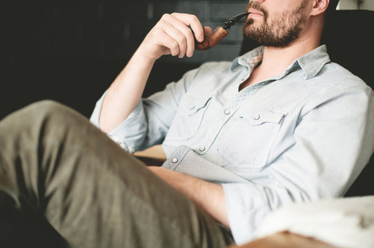 Man sitting in chair, smoking pipe, mid section