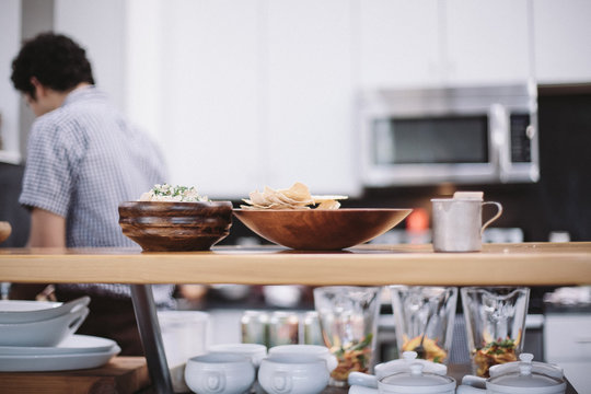 Bowls of food on serving shelf while man preparing food in background