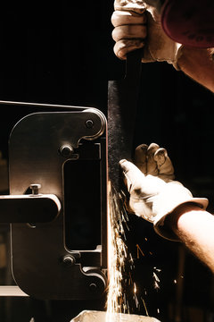 Person sharpening blade of knife on machine, close-up