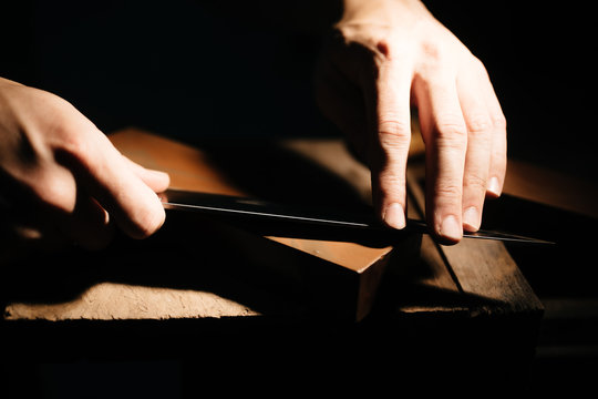 Person sharpening blade of knife, close up