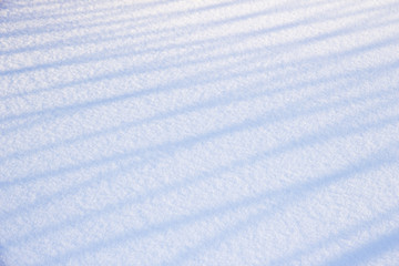 Smooth snow with shadow on a striped fence