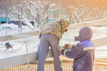 Two workers repairing the roof of the underpass