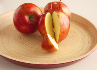 Fototapeta na wymiar Three red apples lie on a wooden plate