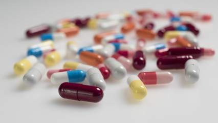 A lot of multi-colored capsules lay on a white background