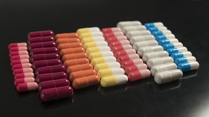 Naklejka premium multi colored capsules neatly stacked on a black background
