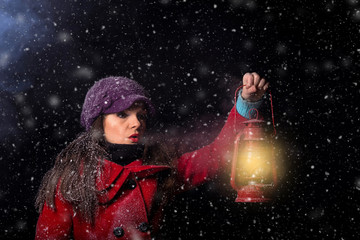 young woman holding lantern in the snowy dark night