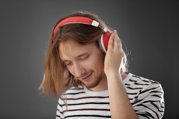 Handsome young man wearing headphones on grey background
