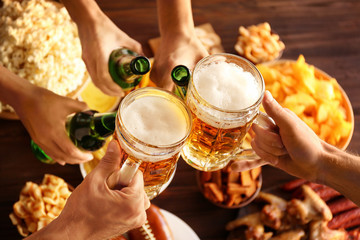 Hands clinking beer mugs and bottles at party, close up