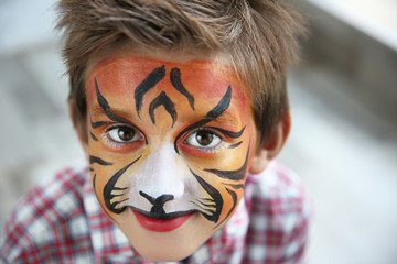 Obraz premium Cute little boy with aqua makeup of tiger muzzle