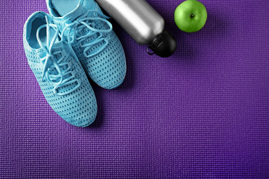 Clothes and items for sport on color background