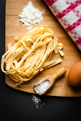 italian tagliatelle displayed on a chopping board together with some ingredients