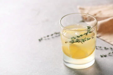 Glass of fresh lemonade on light background