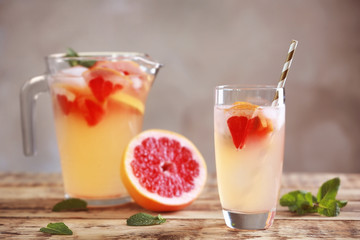 Glass of fresh grapefruit water on grey background