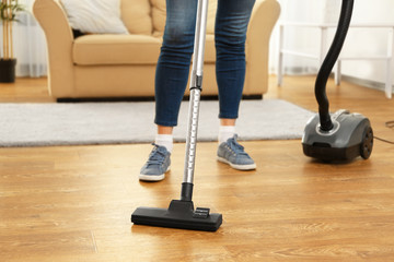 Cleaner hoovering floor in room