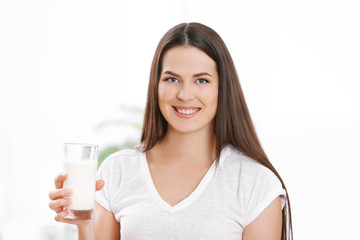 Young attractive woman with glass of milk in kitchen