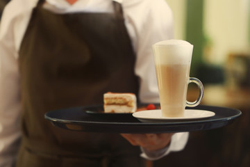 Waiter holding tray with tasty dessert and chocolate drink, close up view