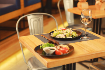 Plates with tasty dishes on wooden table in restaurant