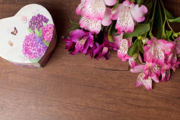 Bouquet of flowers with gift box on a wooden background