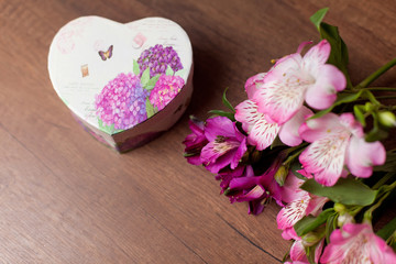Bouquet of flowers with gift box on a wooden background
