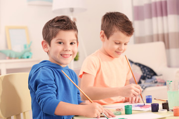 Cute little boys drawing pictures and sitting at table, closeup