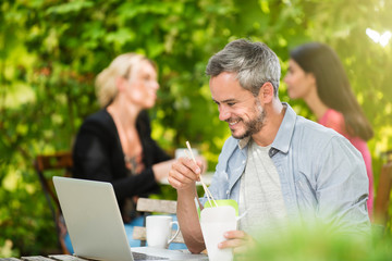 a man eating take away food while working on her laptop