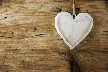 White heart shape hanging on a rustic wooden wall, love concept, valentine's or mother's day