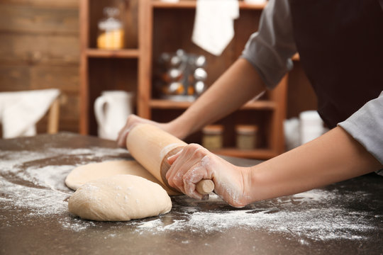 Young woman rolling out dough in kitchen