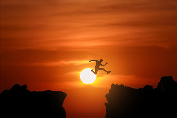 Silhouette Freedom-young man is jumping over precipice between t