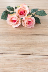 Bouquet of three beautiful pink roses on brown wooden background with lots of copy space.