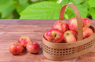 Basket with lying in her red apples on a wooden surface.