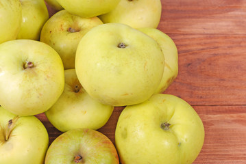 pile of green apples lying on a wooden background
