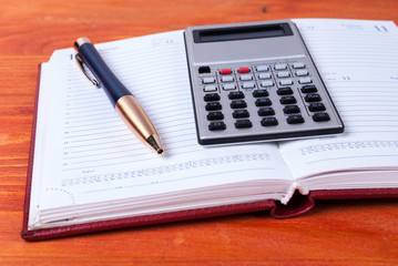 Calculator and pen lie on open diary. Business concept