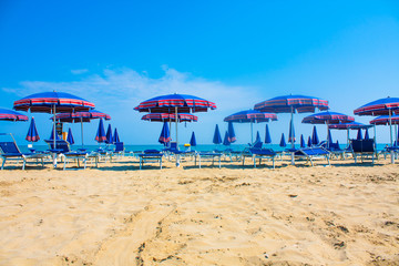 Adriatic Sea coast view. Seashore of Italy, summer umbrellas on sandy beach with clouds on horizon.