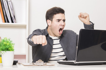 young man celebrating enthusiastically in front of laptop computer