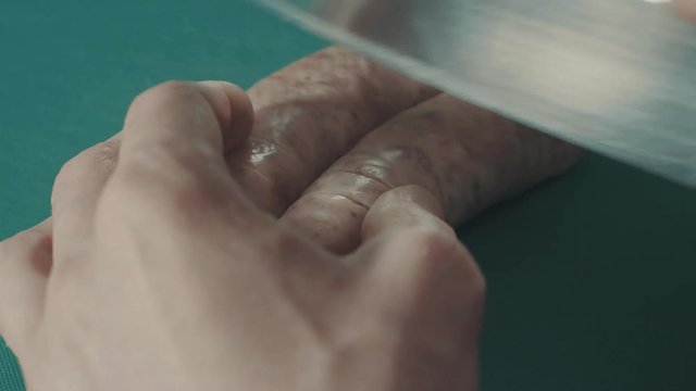 Man cuts some sausages on the plastick board